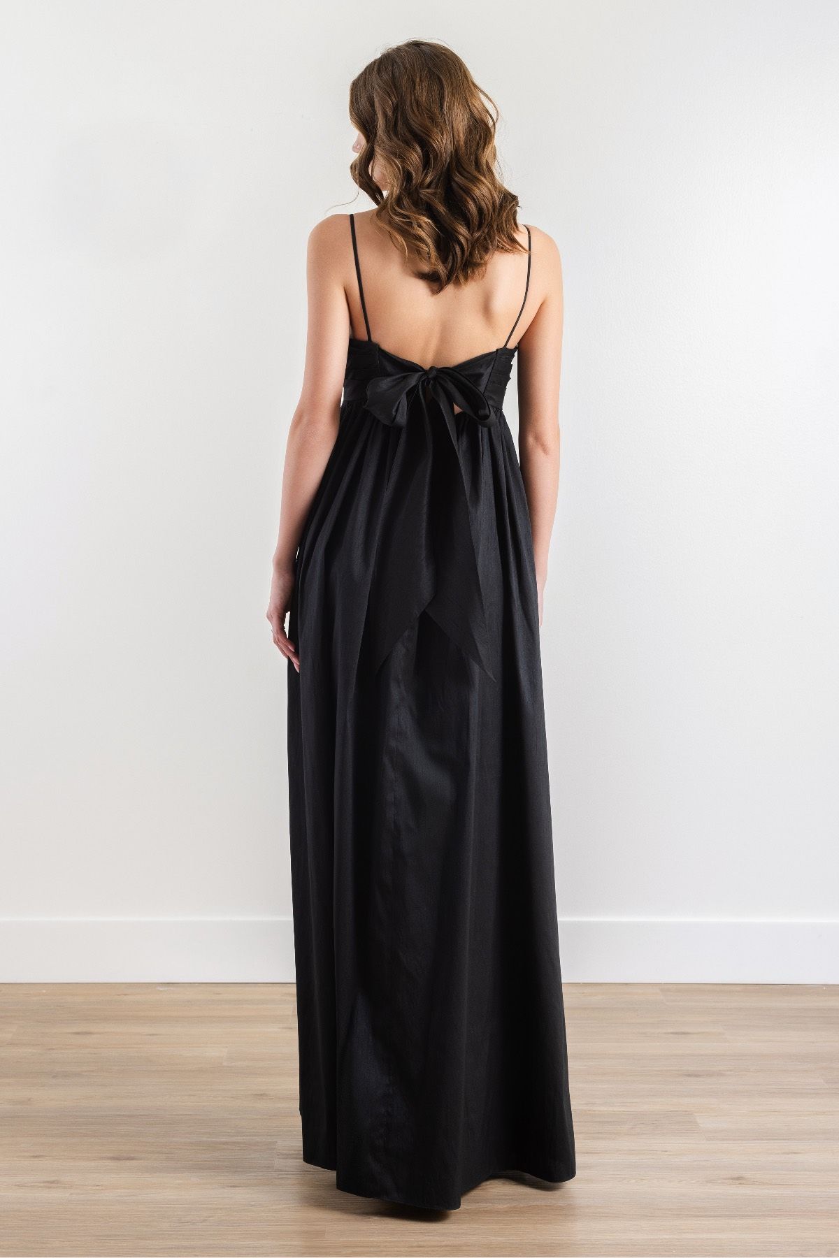 The back of a woman wearing a black dress is shown.