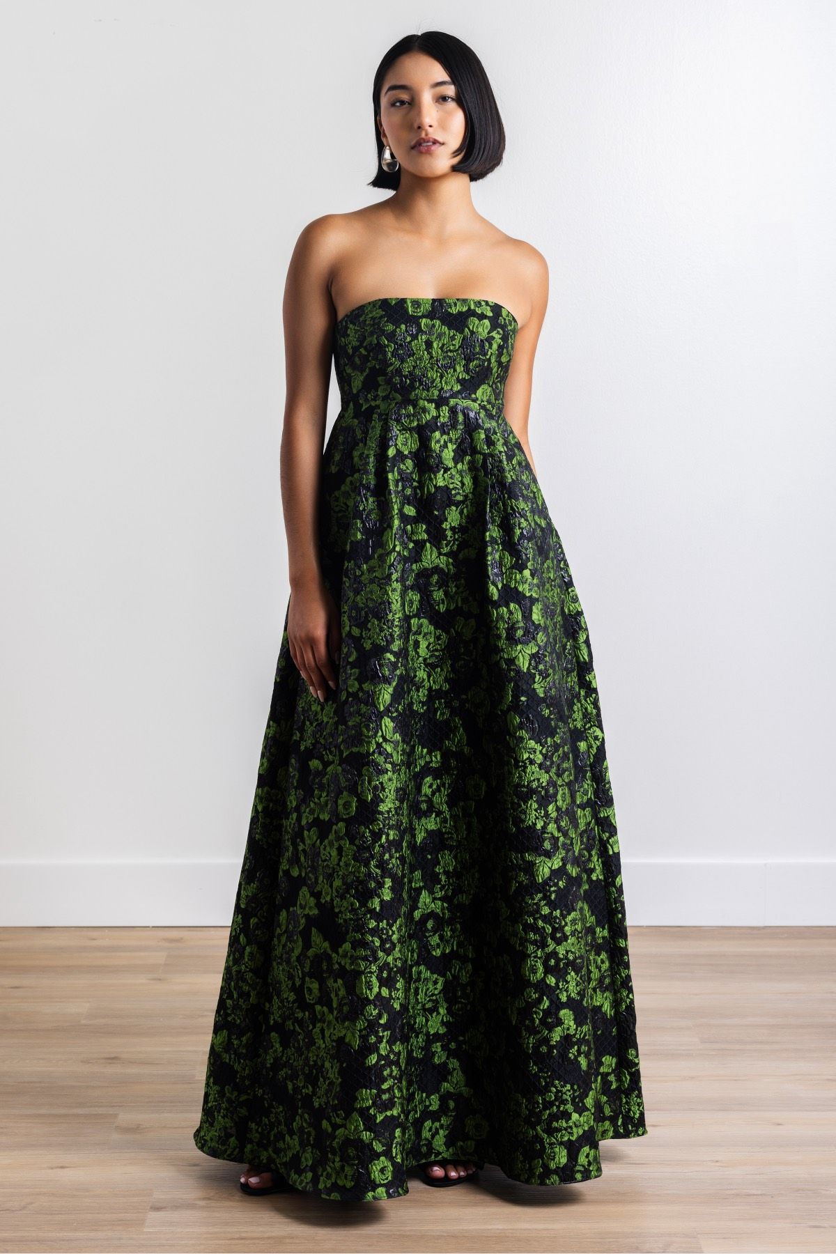 A woman is wearing a strapless green and black dress.