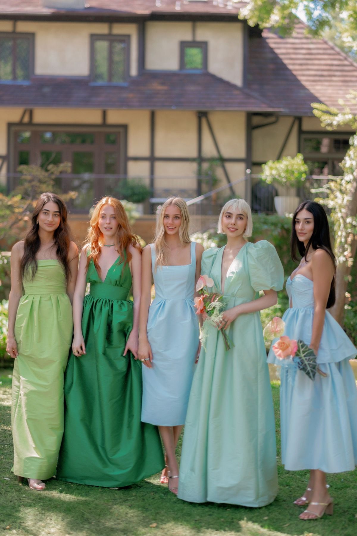 A group of women are posing for a picture in front of a house.
