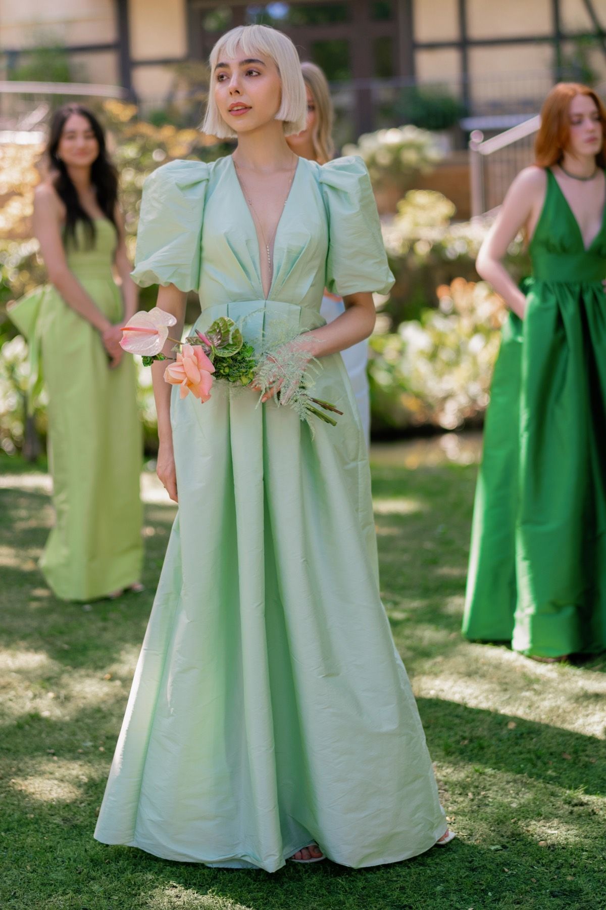 A woman in a green dress is holding a bouquet of flowers.
