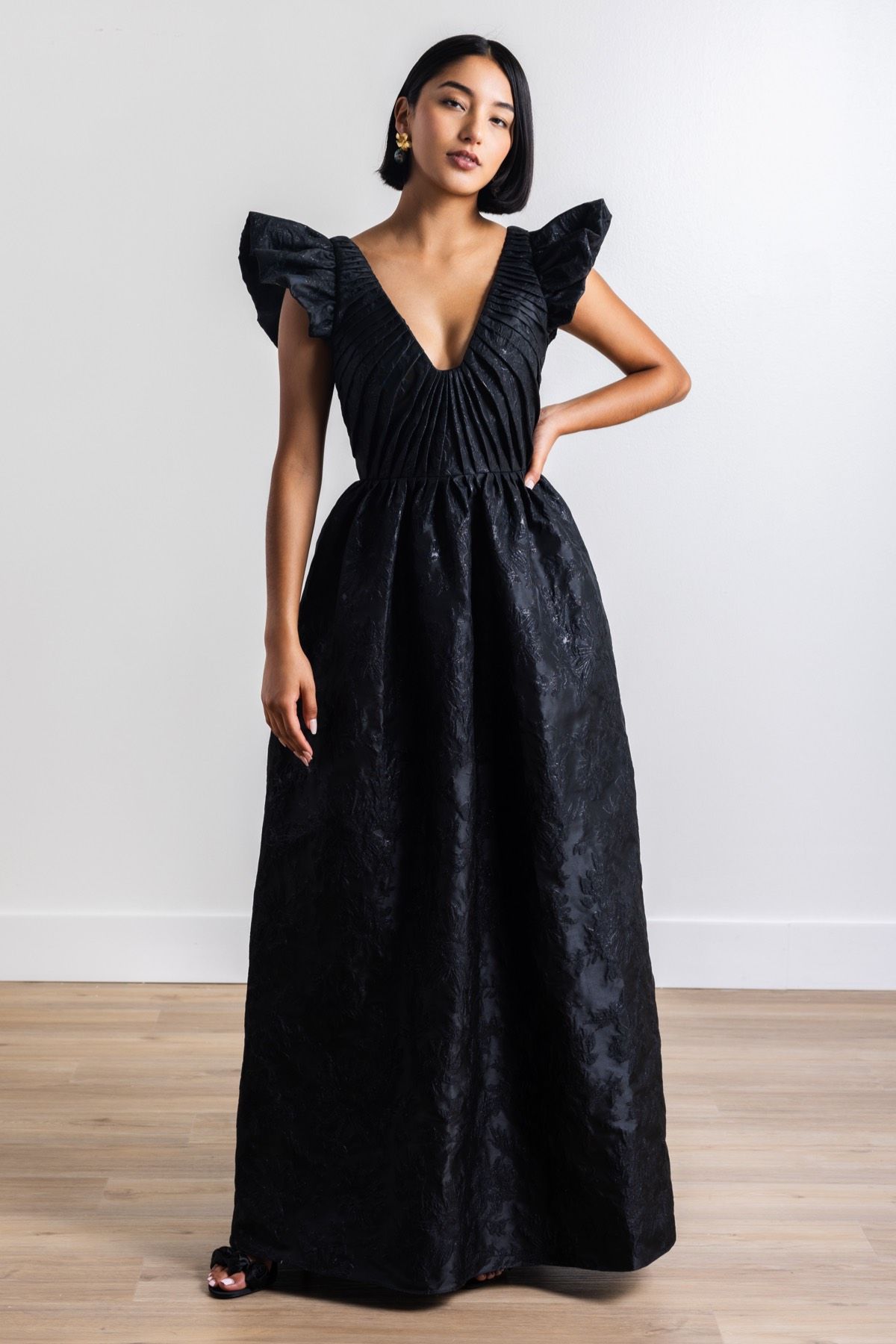 A woman in a black dress is standing on a wooden floor.