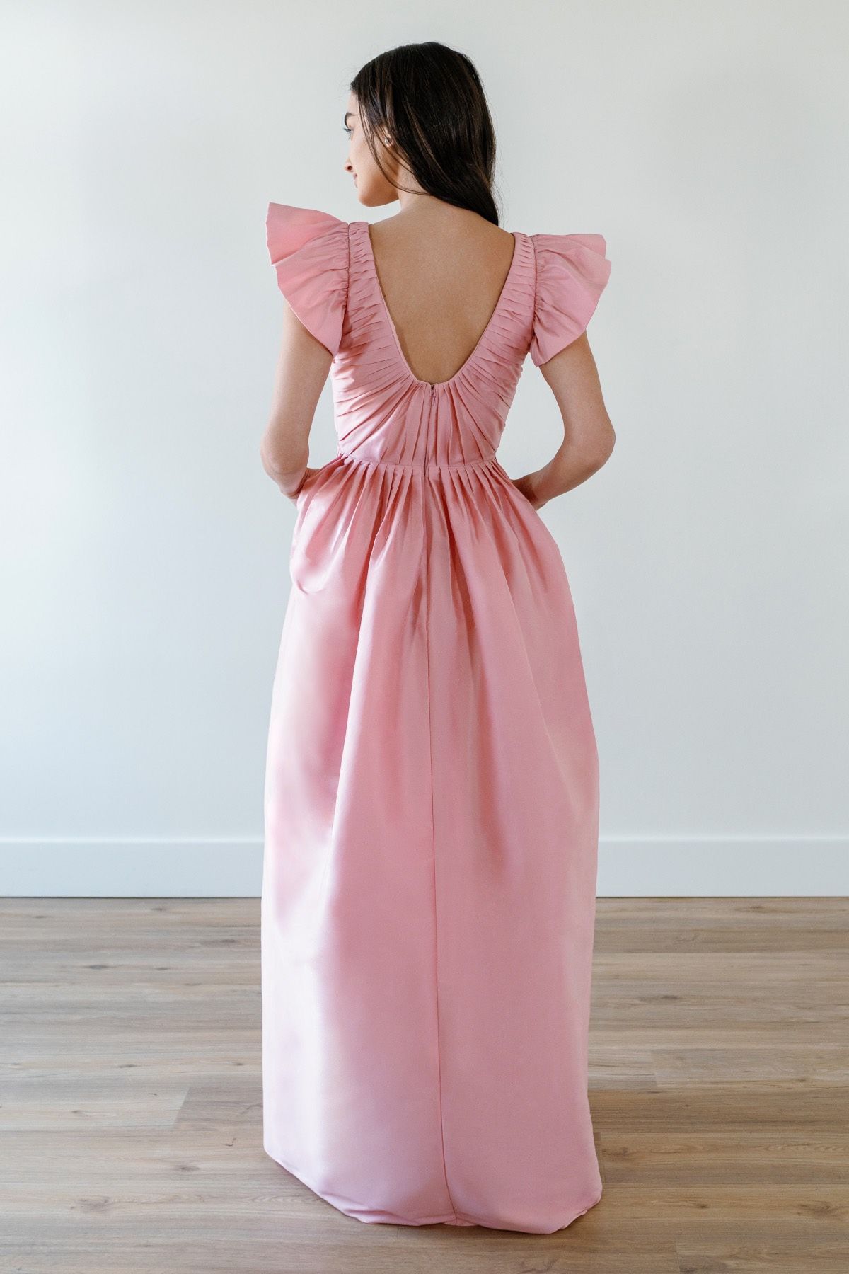 The back of a woman wearing a pink dress with ruffled sleeves.