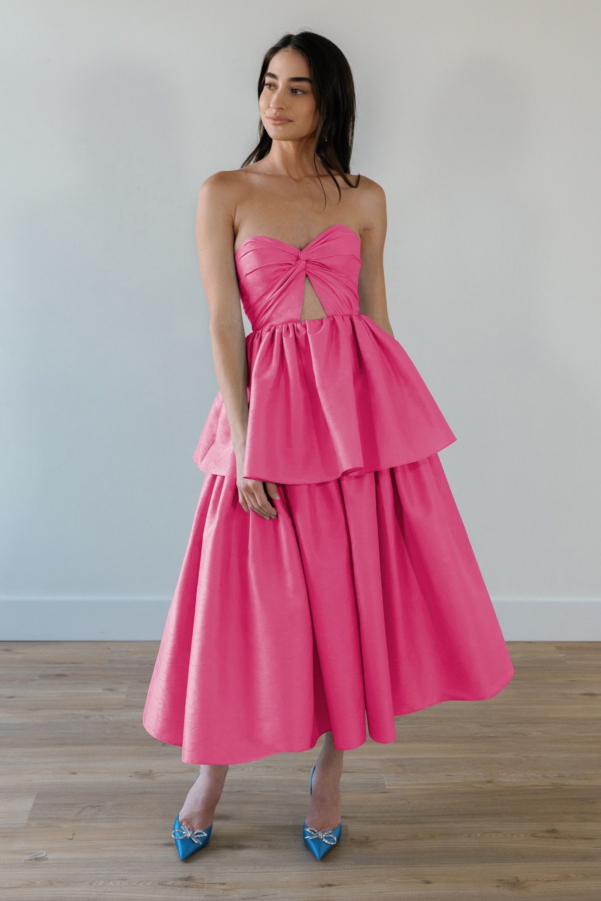 A woman is wearing a pink strapless dress and blue shoes.