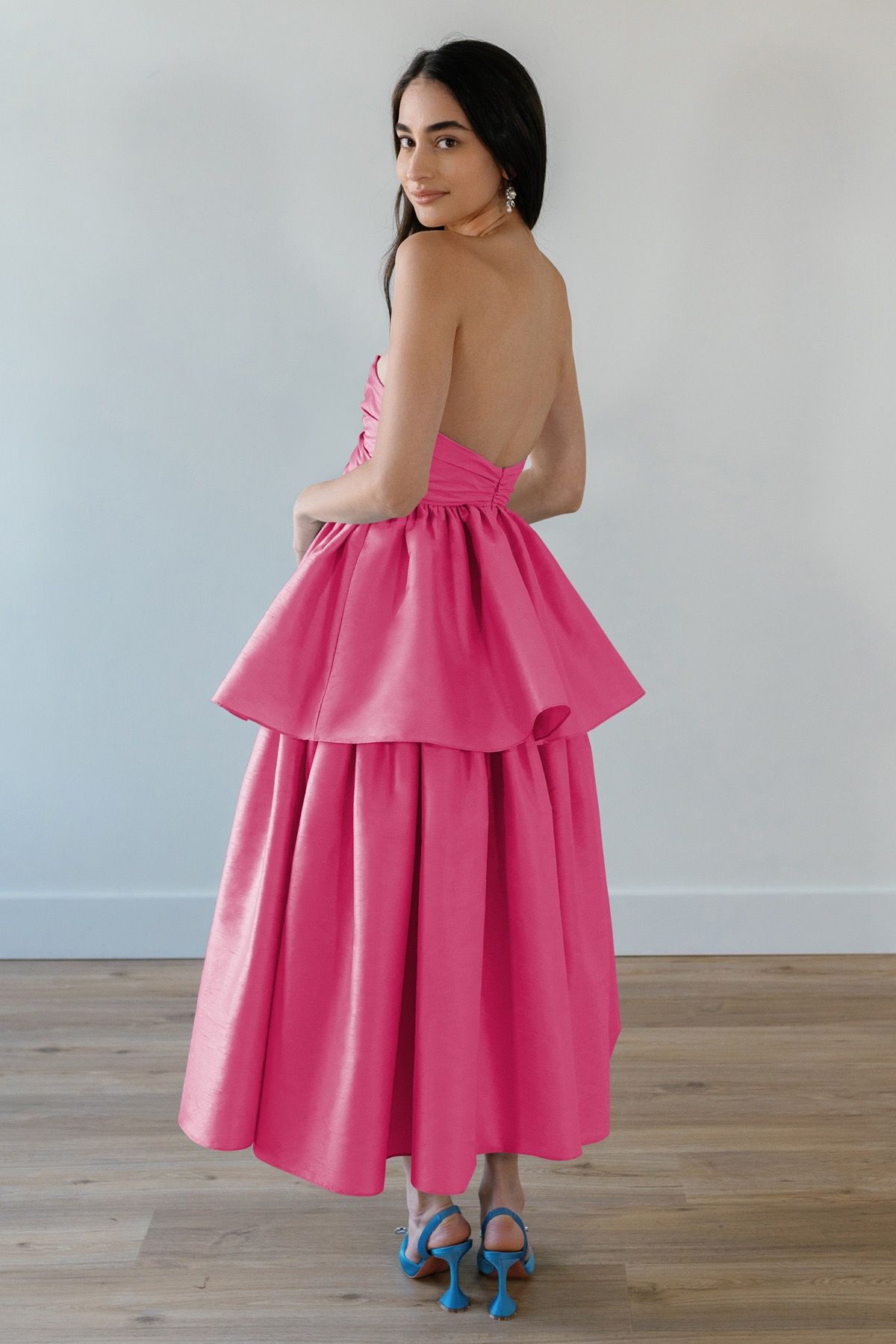 A woman is wearing a pink dress and blue shoes.