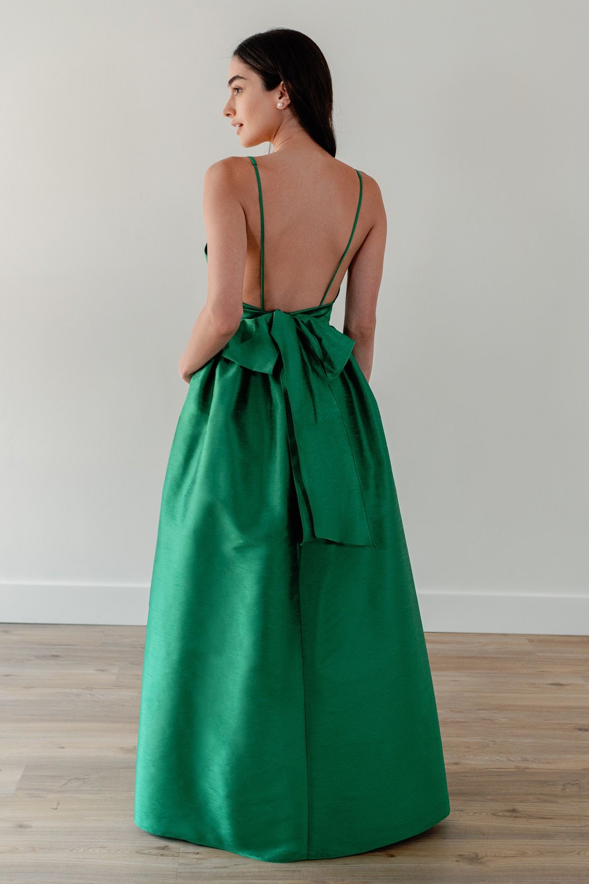 A woman is wearing a green dress with a bow on the back.