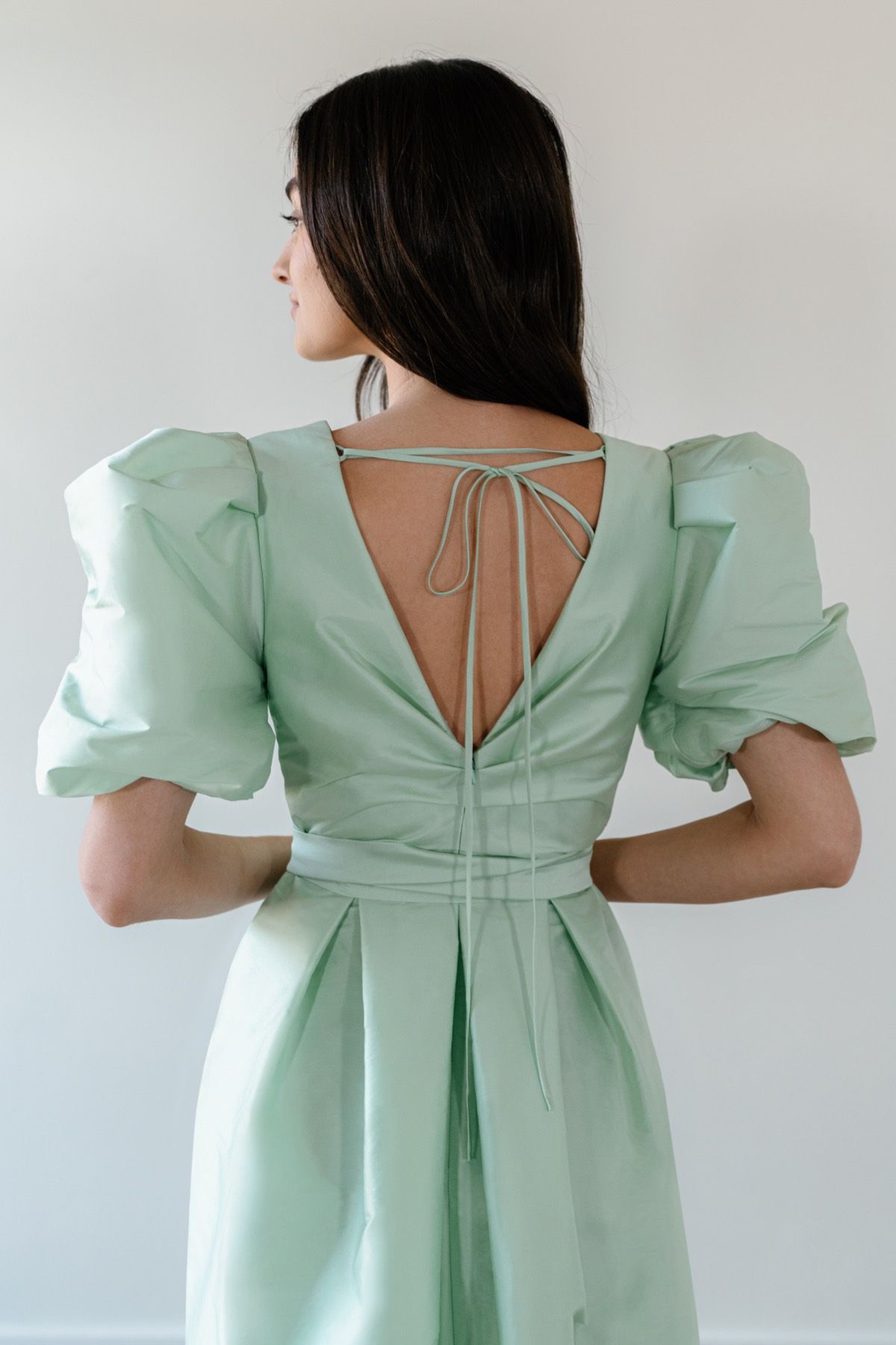The back of a woman wearing a mint green dress with puffed sleeves.