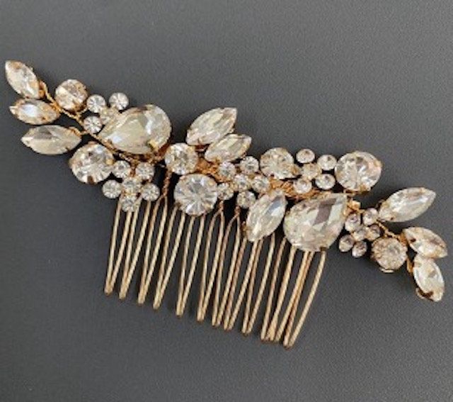 A gold hair comb with lots of rhinestones on it