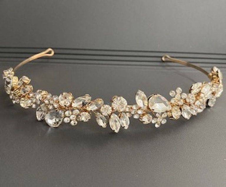 A gold headband with rhinestones on it is sitting on a table.
