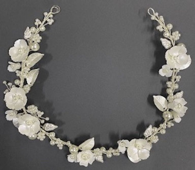 A necklace with white flowers and pearls on a grey background