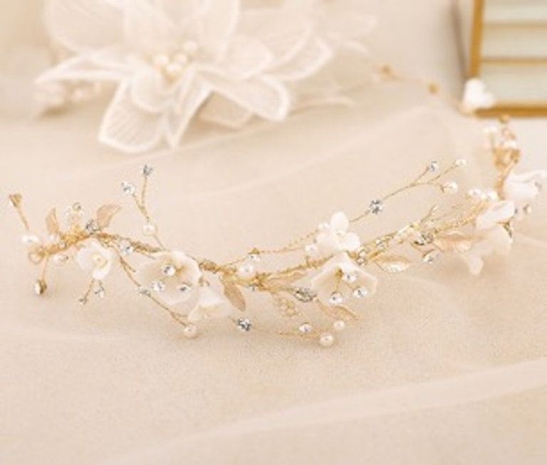 A headband with white flowers and pearls is sitting on a table.