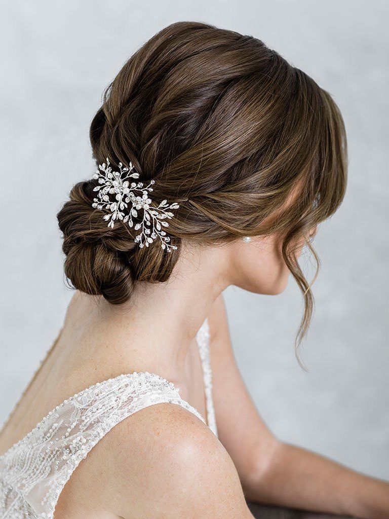 A woman in a wedding dress is wearing a hair clip in her hair.