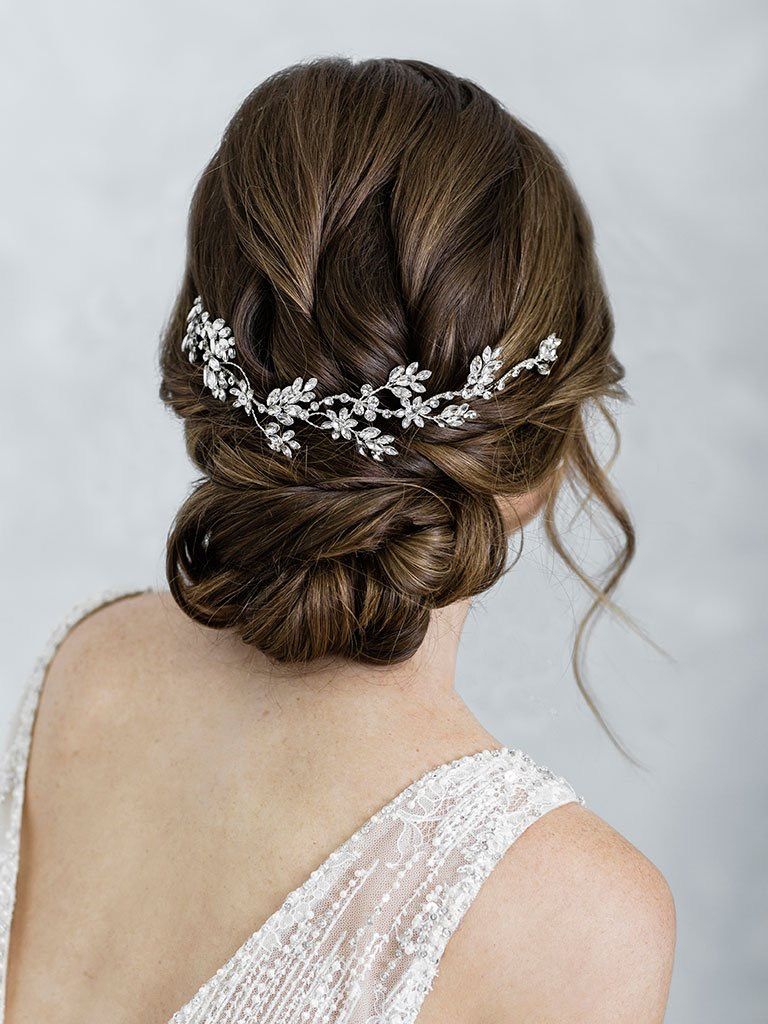 A woman in a wedding dress is wearing a headpiece in her hair.