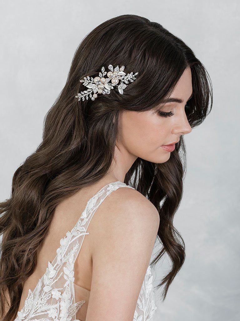 A woman in a wedding dress is wearing a hair clip in her hair.