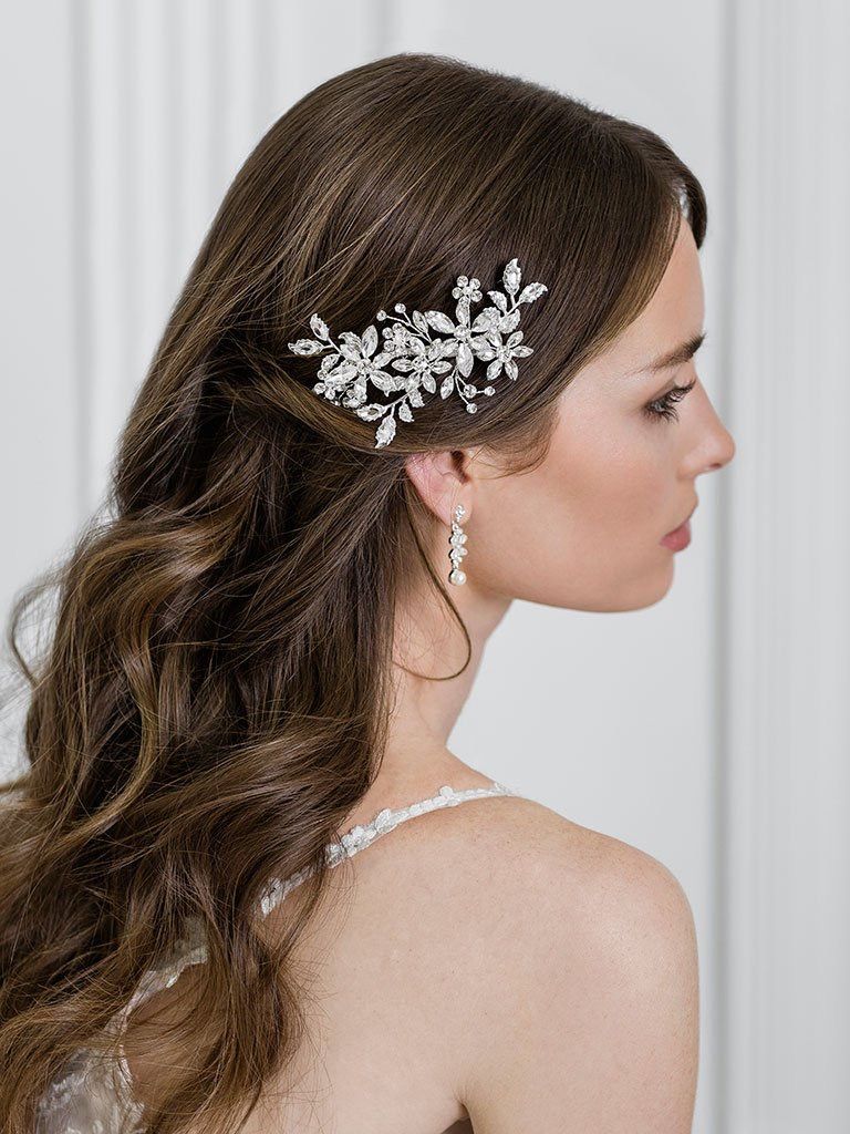 A woman in a wedding dress is wearing a hair comb and earrings.