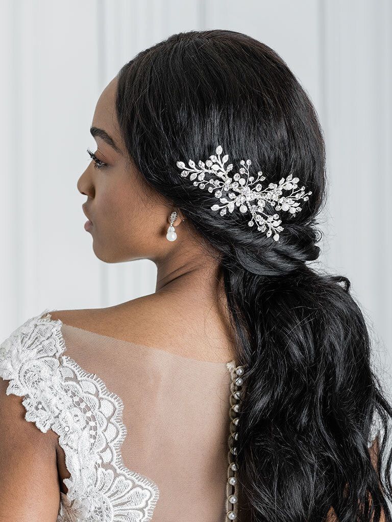 A woman in a wedding dress is wearing a hair comb and earrings.