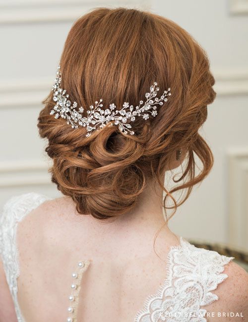 A woman in a wedding dress is wearing a headpiece in her hair.