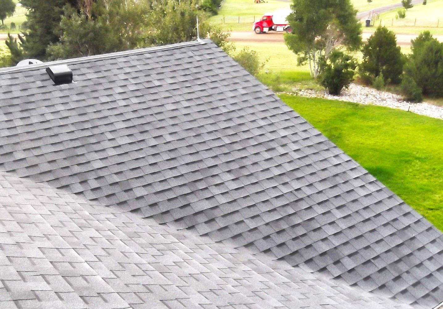 A roof of a house with a red truck in the background
