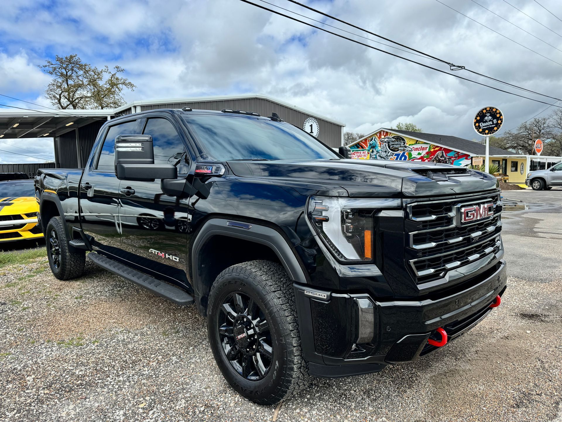 Black GMC Sierra truck parked on gravel in front of a store.