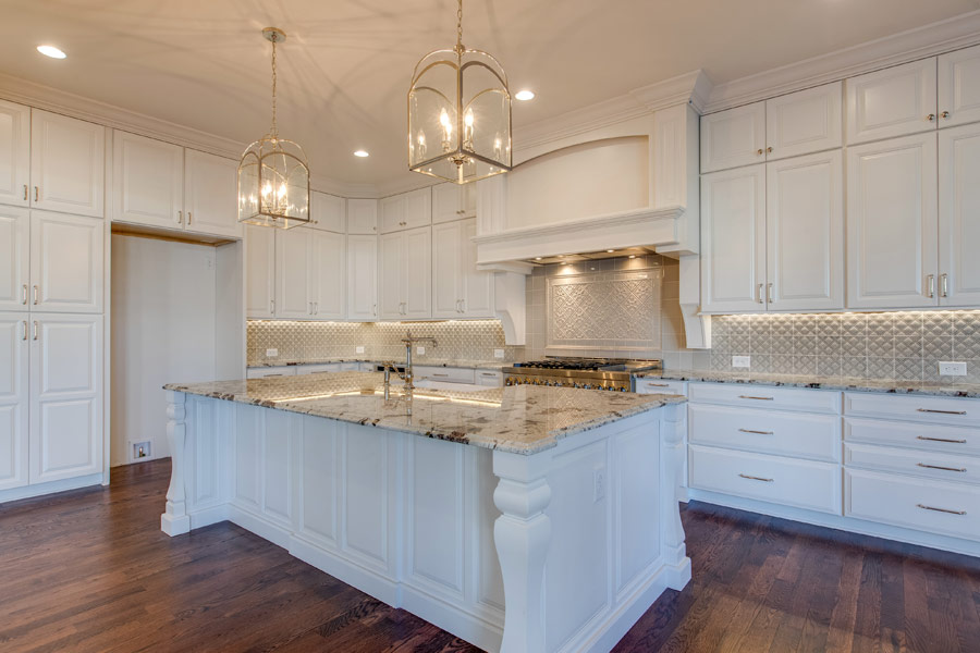 A kitchen with white cabinets , granite counter tops , and a large island.