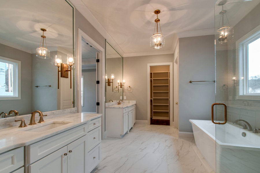 A bathroom with two sinks , a tub , and a walk in closet.