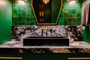 A bathroom with green tiles and a black sink.