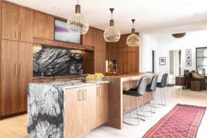 A kitchen with a large island and stools and a rug.