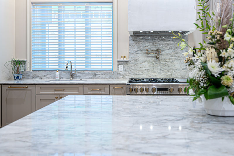 There is a vase of flowers on the counter in the kitchen.