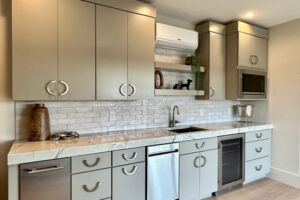 A kitchen with white cabinets , stainless steel appliances , a sink , and a refrigerator.