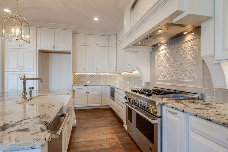A kitchen with white cabinets , granite counter tops , stainless steel appliances and a large island.