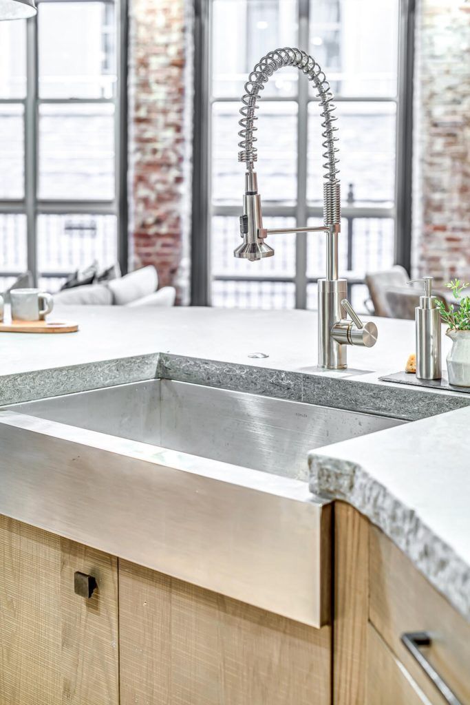 A kitchen sink with a faucet and a window in the background.