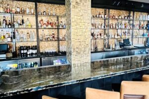 A long bar in a restaurant with a lot of alcohol on shelves.