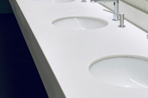 A row of white sinks with chrome faucets in a bathroom.