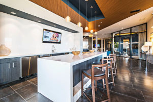 A kitchen with a large island and stools and a flat screen tv on the wall.