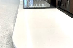A white counter top with a black counter top in a kitchen.