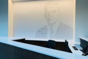 A picture of a man in a suit and tie is on a wall above a desk.
