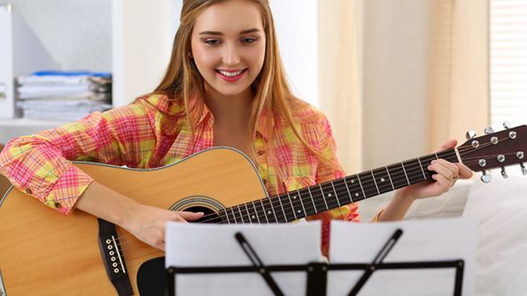 Woman playing guitar a guitar while reading on her written song