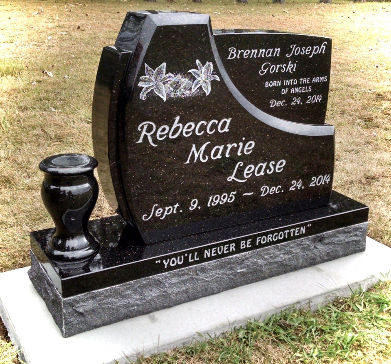 Black granite headstone with floral carvings, a small vase, and inscriptions for Rebecca Marie Lease and Brennan Gorski.