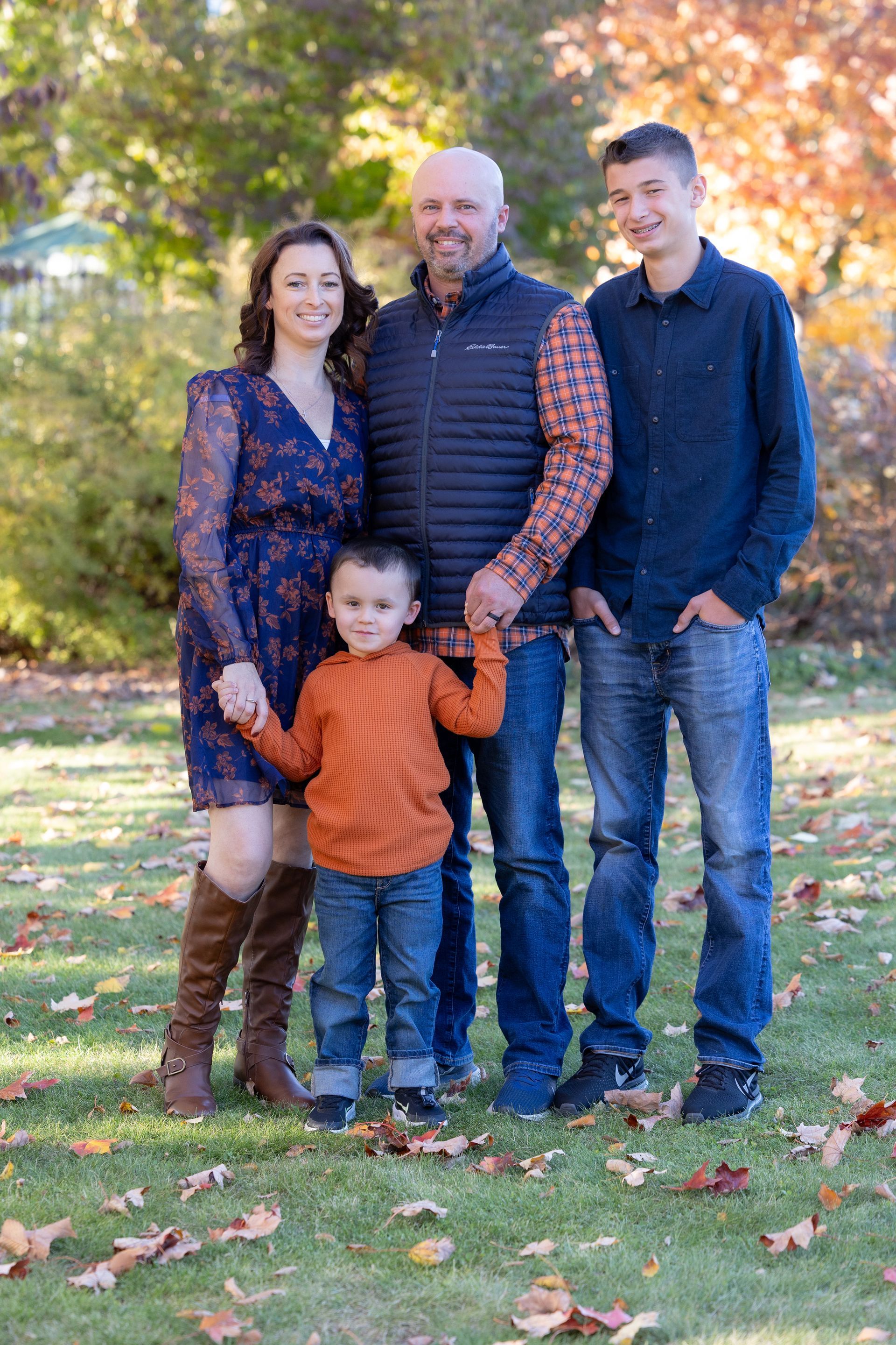 A family is posing for a picture in front of a white fence.