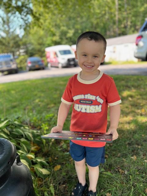 A young boy wearing a red shirt that says autism