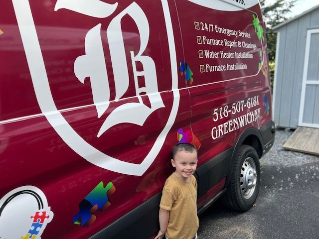 A young boy is standing in front of a red van.
