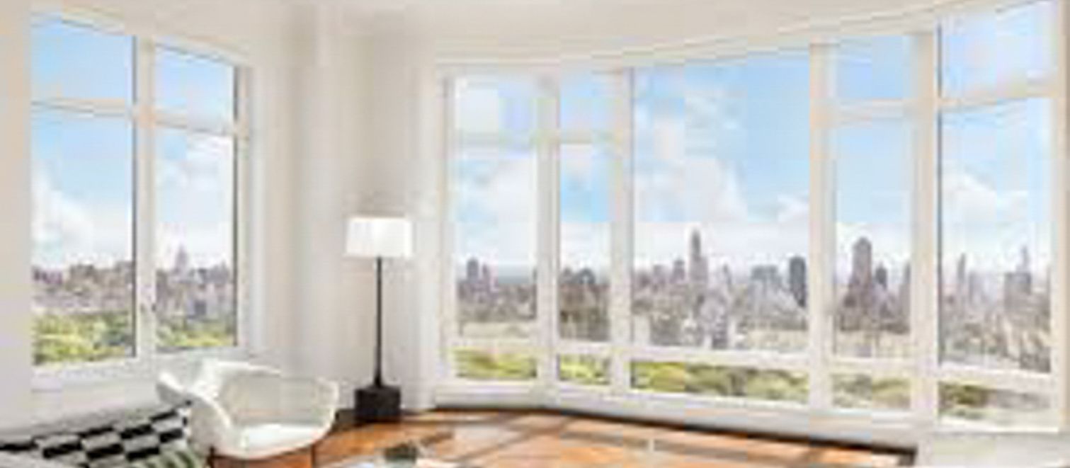 Bright living room with large windows, city skyline view, white chair, floor lamp, and patterned rug