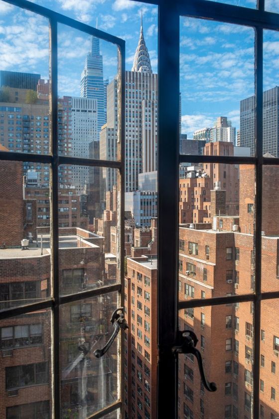 City skyline seen through a black-framed window on a sunny day.
