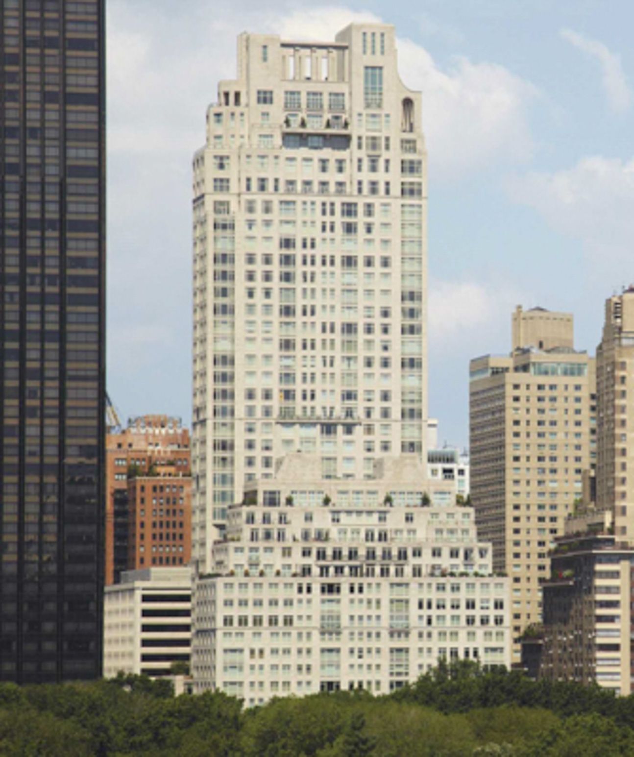 Tall white Art Deco skyscraper among other city buildings under a cloudy sky