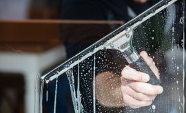 Worker cleaning a glass window with a squeegee in an upper east side apartment