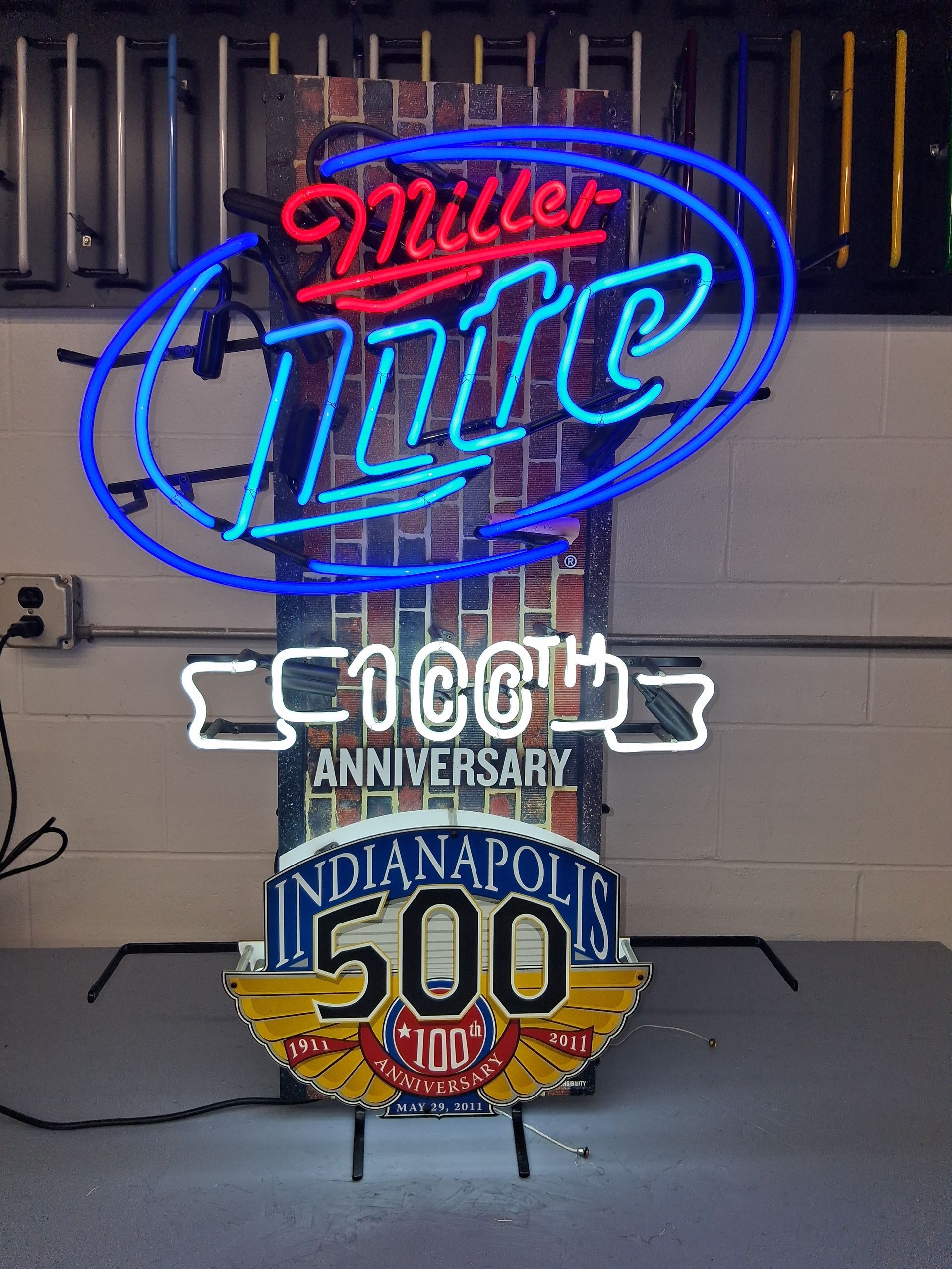 Neon Miller Lite sign with a COOGH anniversary Indianapolis 500 plaque on a stand