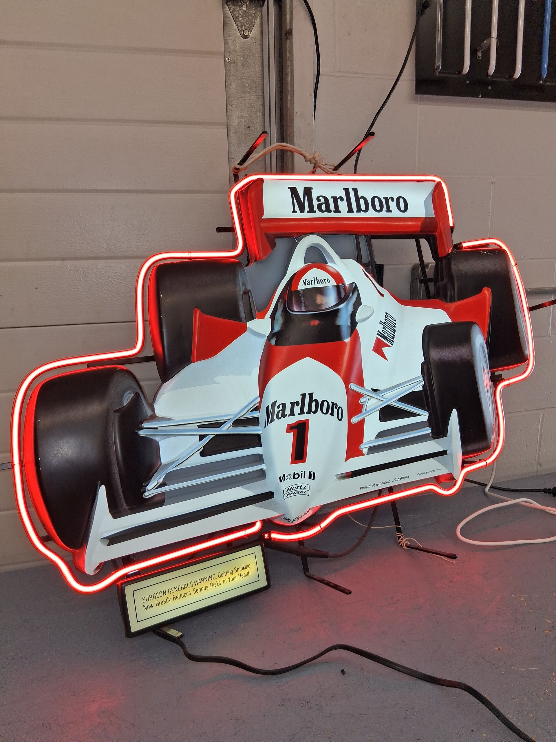 Marlboro Formula 1 car sign with red neon outline on a stand indoors