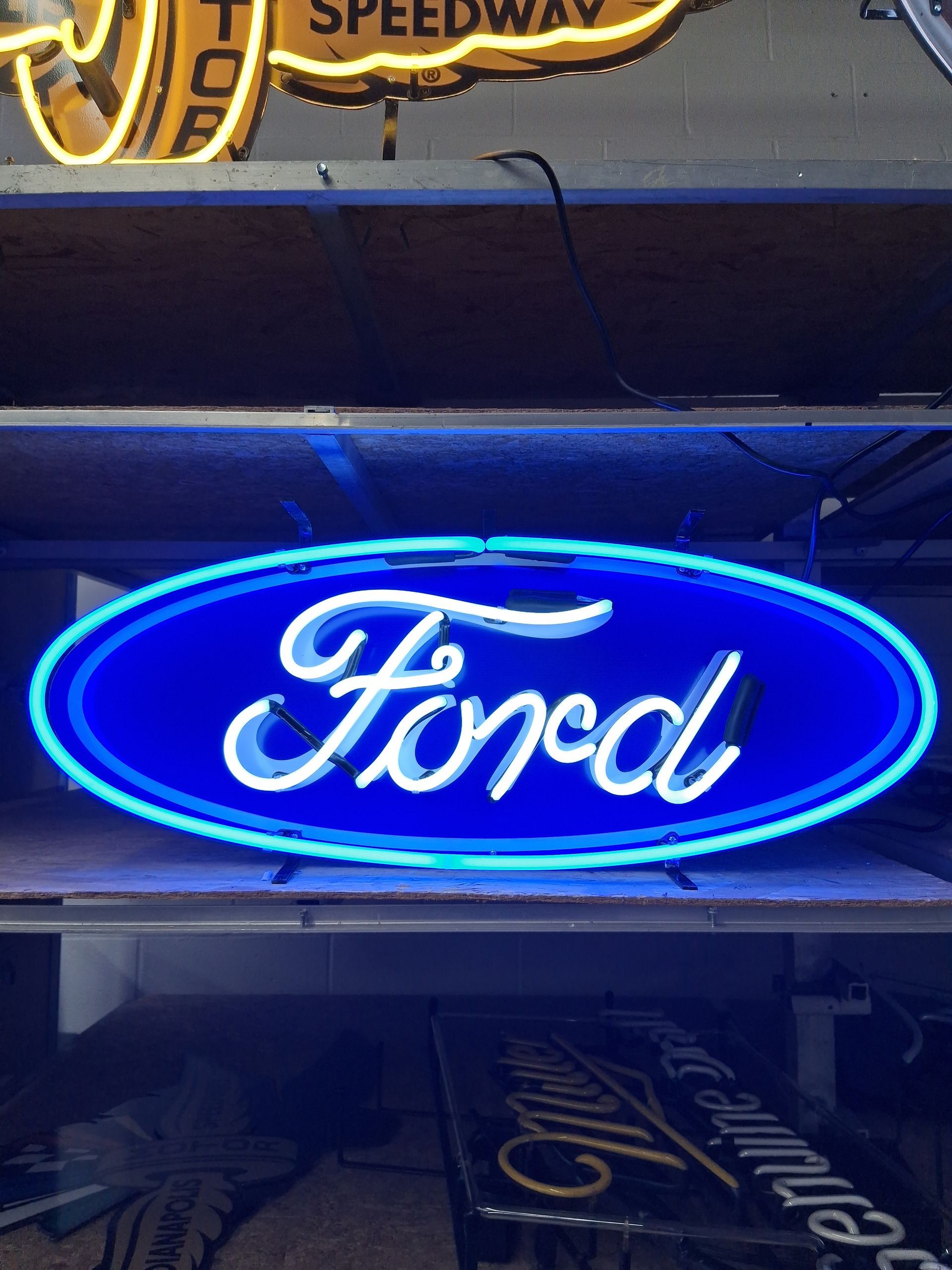 Blue neon Ford oval sign glowing on a dark storefront wall.