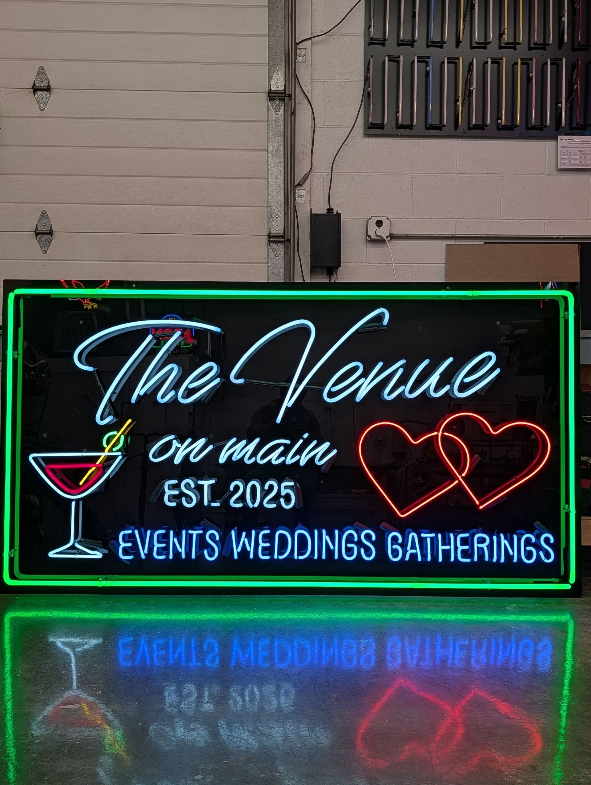 Neon sign for “The Venue” bar and event space, with cocktail glass and heart outlines at night
