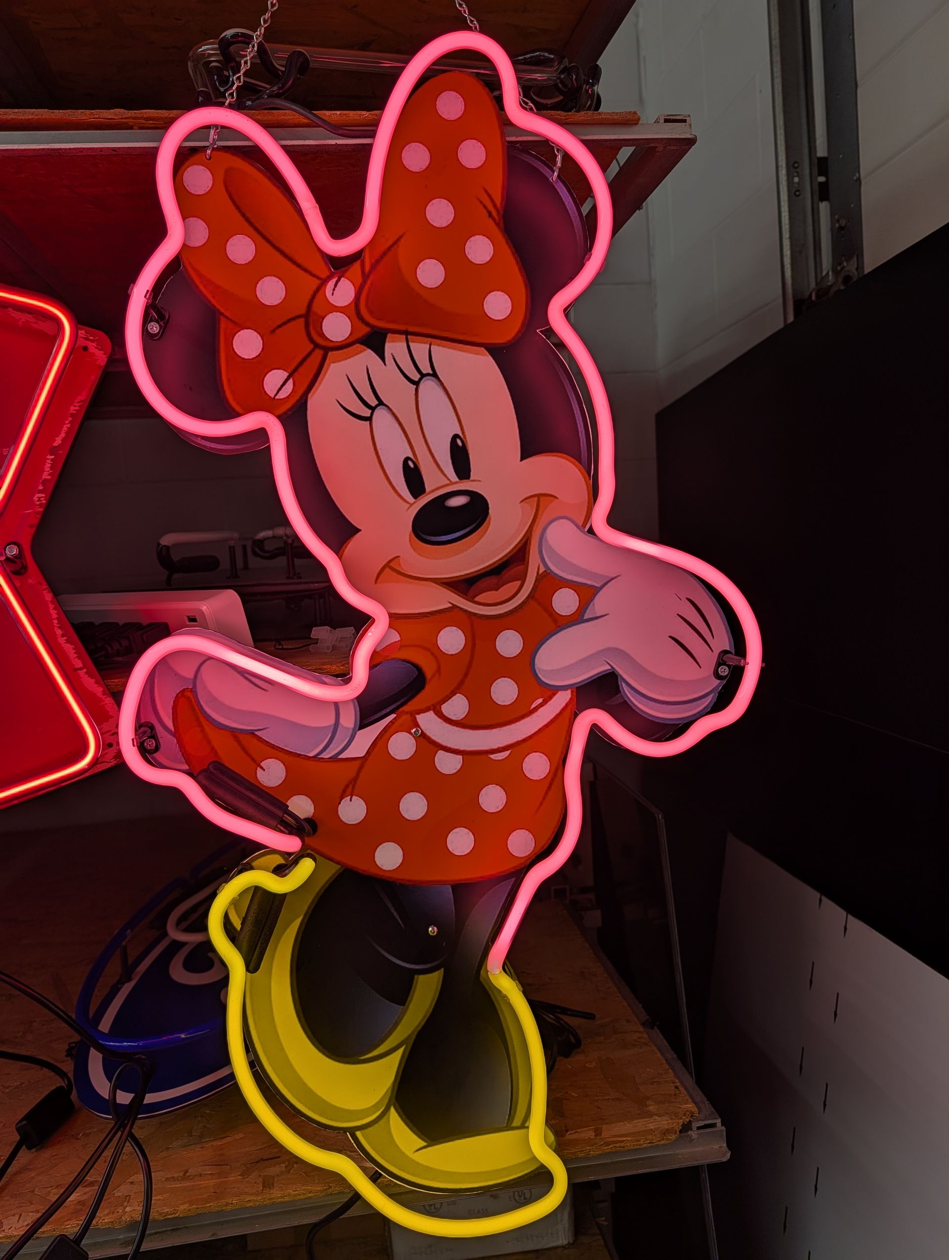 Minnie Mouse neon sign in pink and yellow, wearing a polka-dot dress and bow.