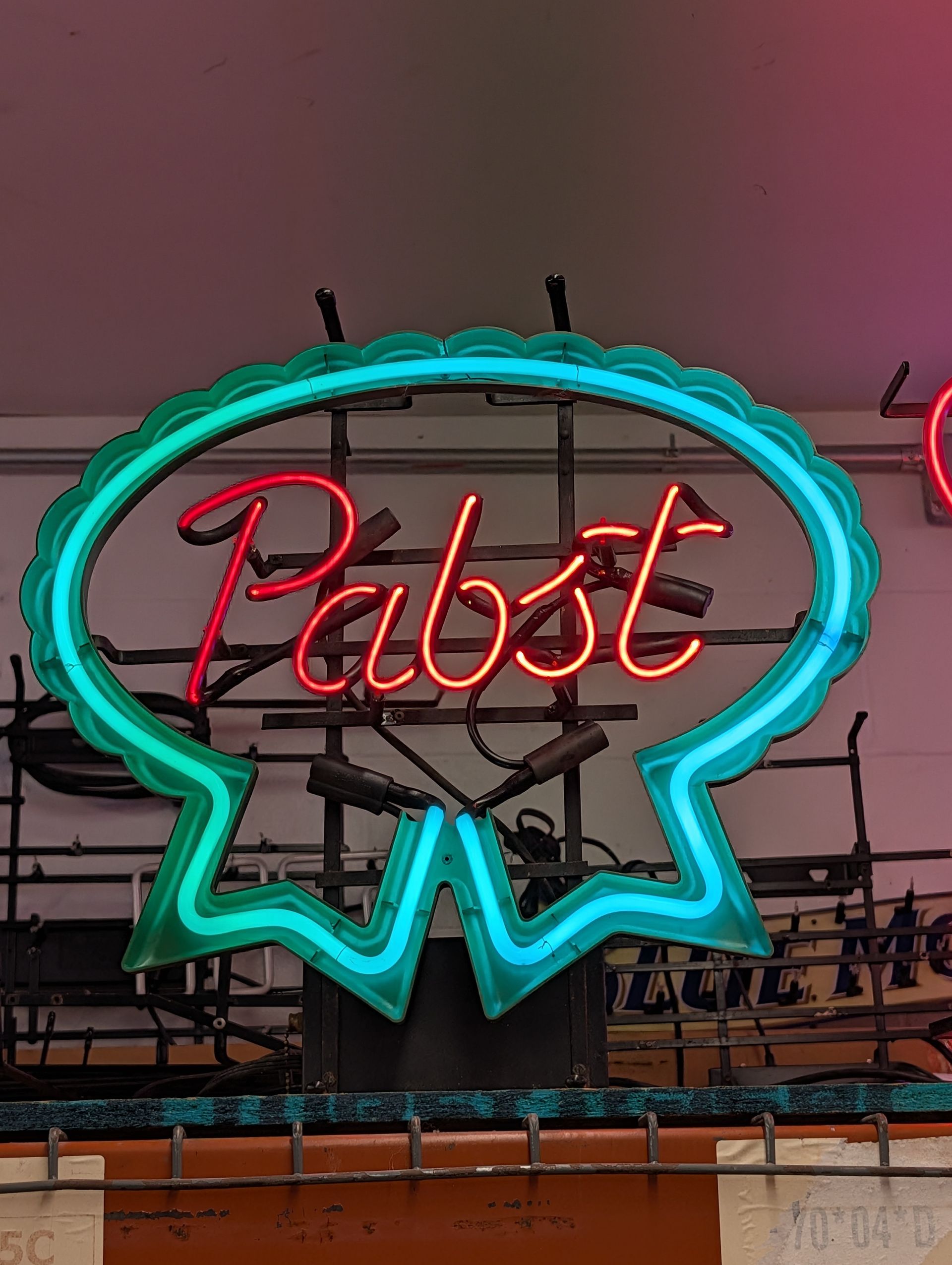Pabst neon sign glowing red and cyan against a dim bar ceiling